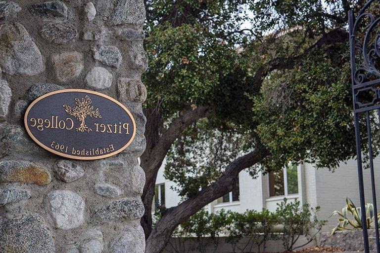 A closeup of the the Pitzer College bronze plaque on the stone pillar of the Pitzer Gate